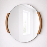 Round mirror with wooden frame on a white wall