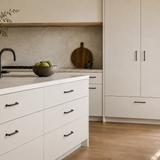A modern kitchen with light neutral accents - dark black nickle handle throughout