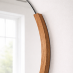 Round mirror with a wooden handle on a white wall