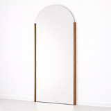 Tall, thin mirror with a wooden frame on a white background
